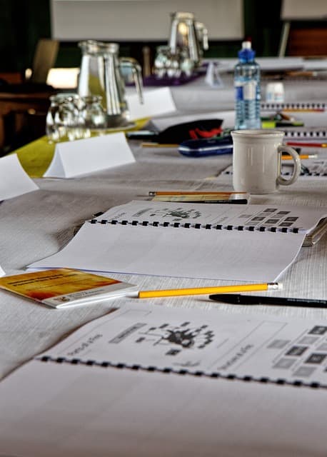 A meeting room table set with notebooks, pens and refreshments ready for a workshop session